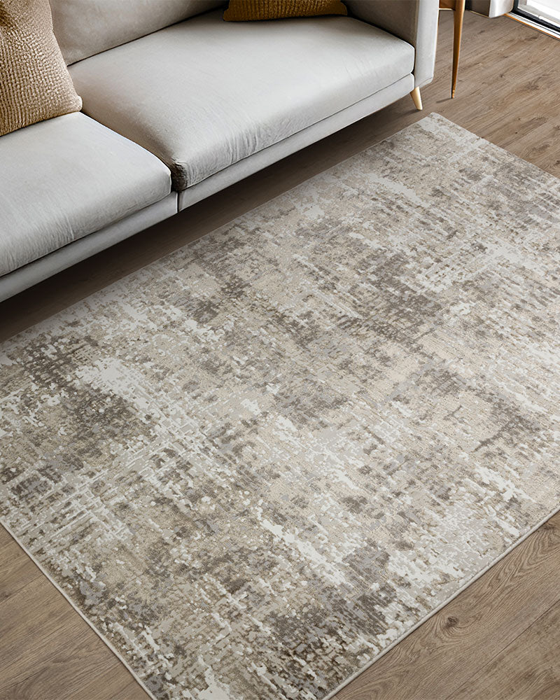 beige bronze area rug on a wooden floor in a living room setting with a sofa.